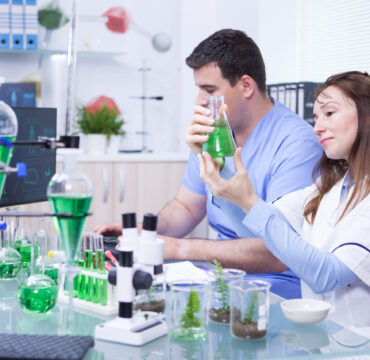 Middle age woman with her assistant working in a research lab for microbiology. Test tubes.